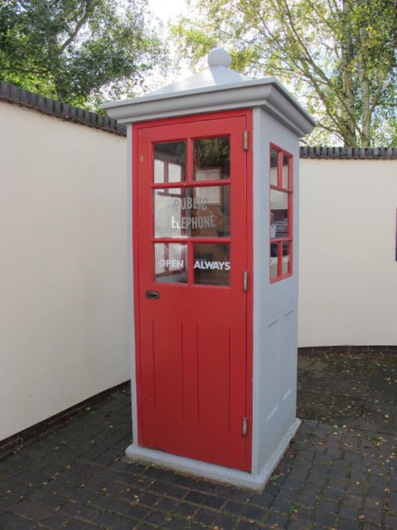 A K1 telephone kiosk, painted grey with a red door